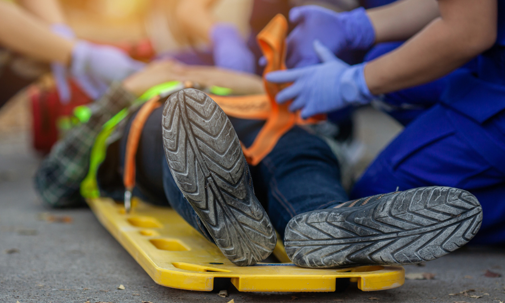 Injured man lays on a gurney while medical personnel strap him down for safety