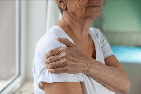 Senior woman clutches her shoulder in pain after suffering an injury
